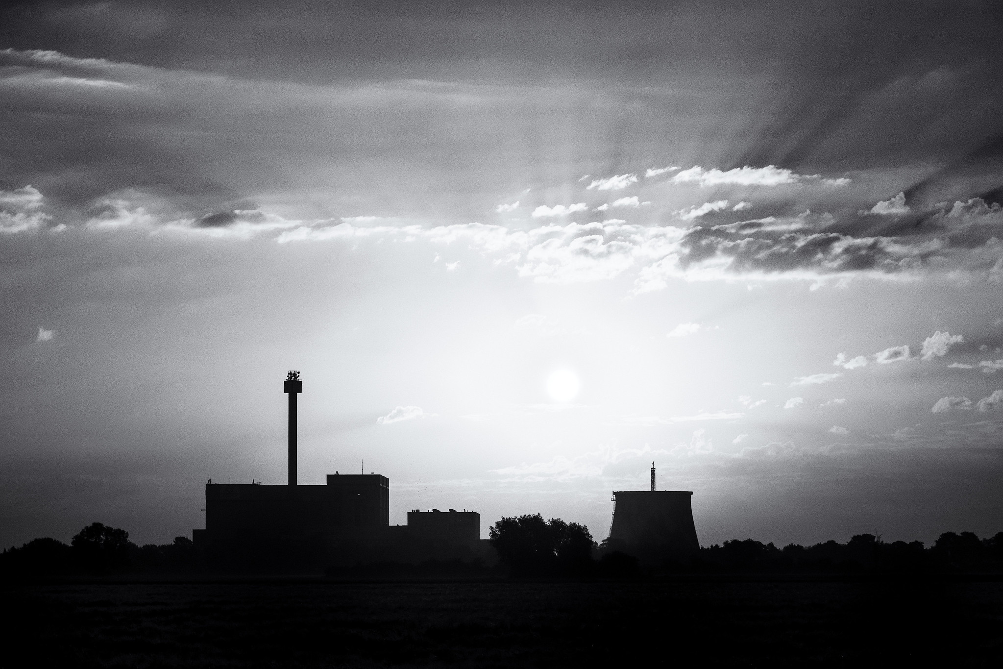 Industrial power station silhouetted beneath a cloudy sky