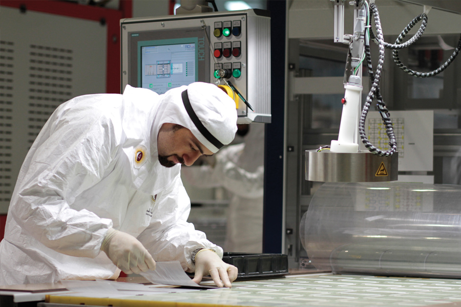 Technician in protective clothing working at manufacturing equipment