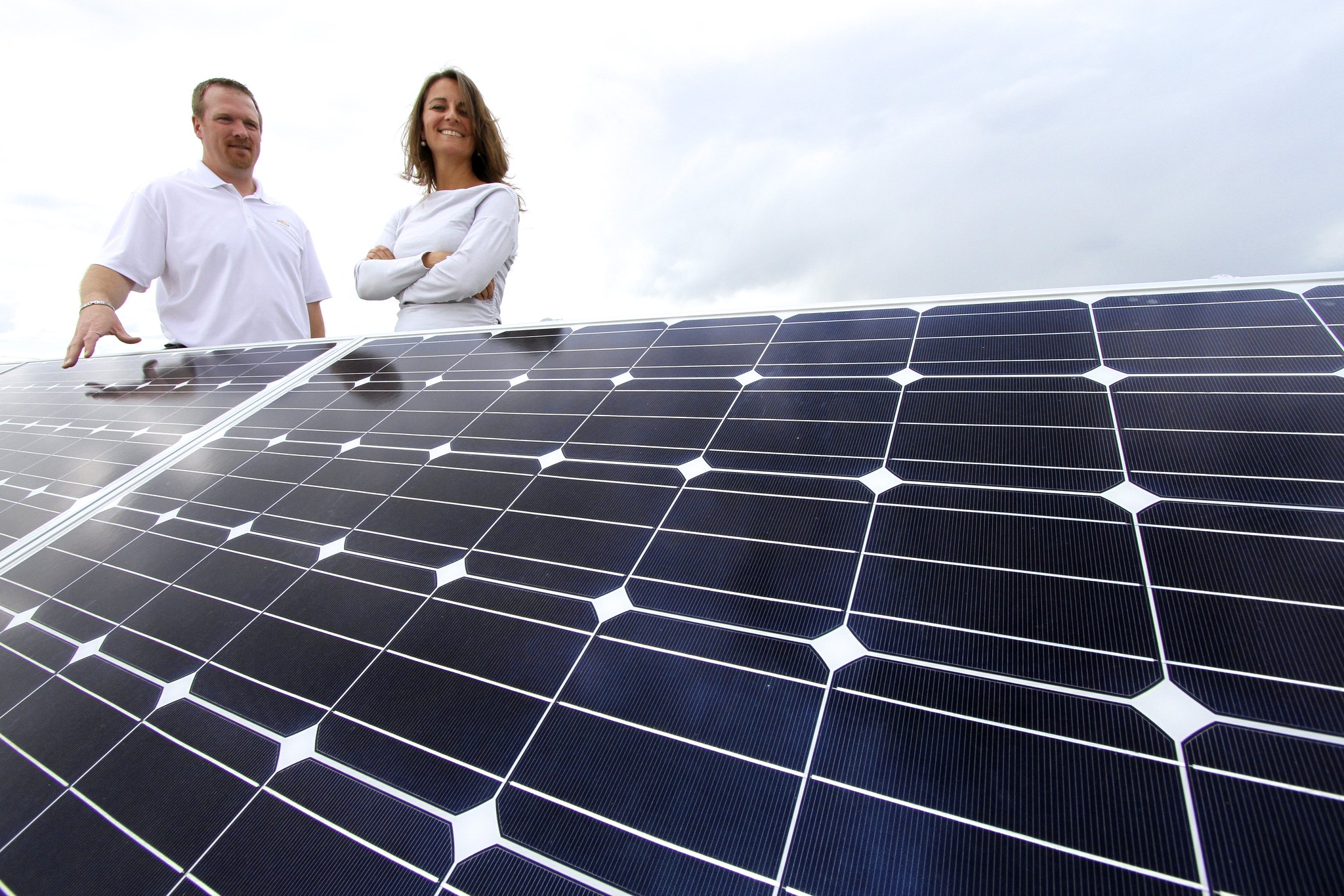 Two people standing behind photovoltaic panels