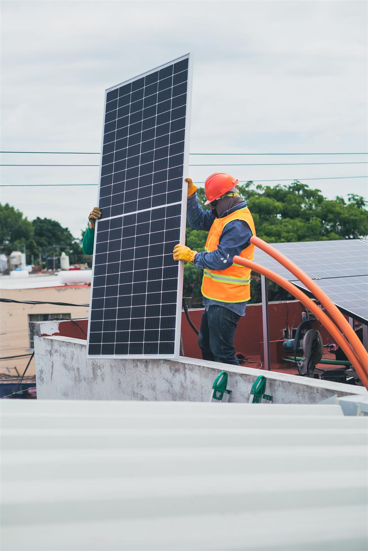 Worker carrying a solar panel on a rooftop