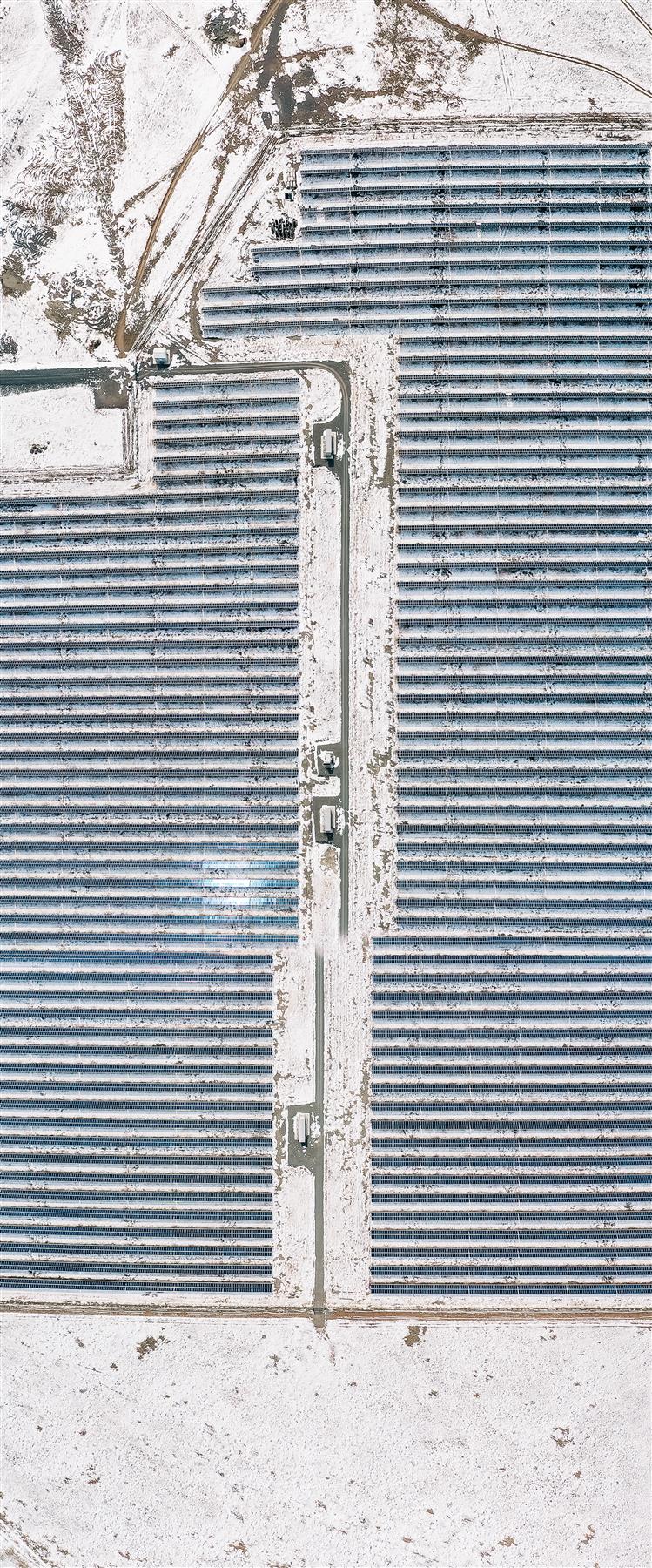Snow-covered rows of solar panels seen from above