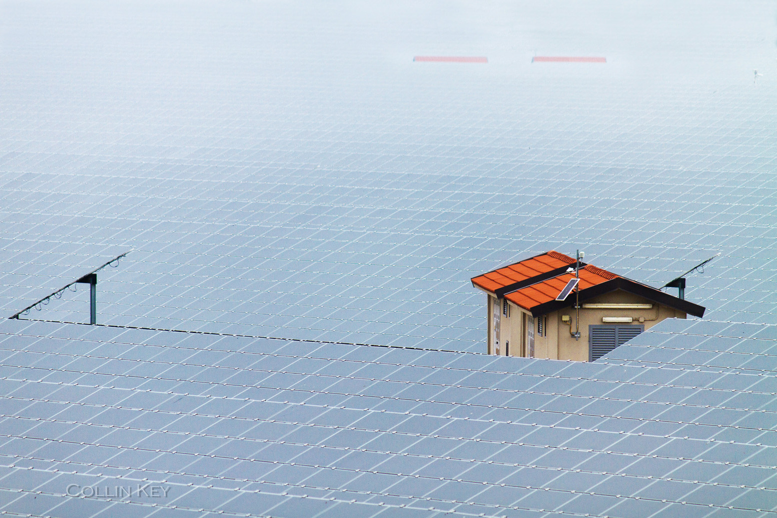 Rows of solar panels surrounding a small red-roofed building