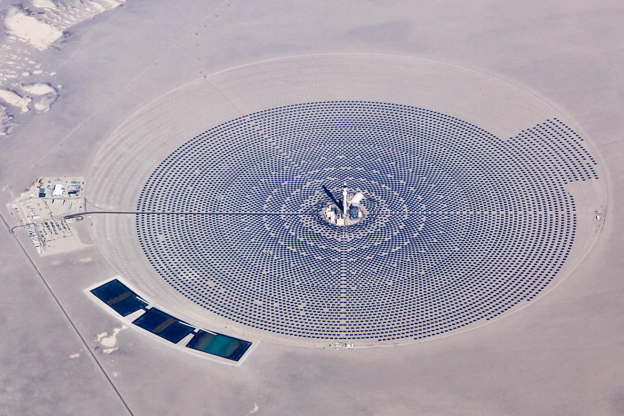 Aerial view of mirrors arranged around a solar tower in a desert