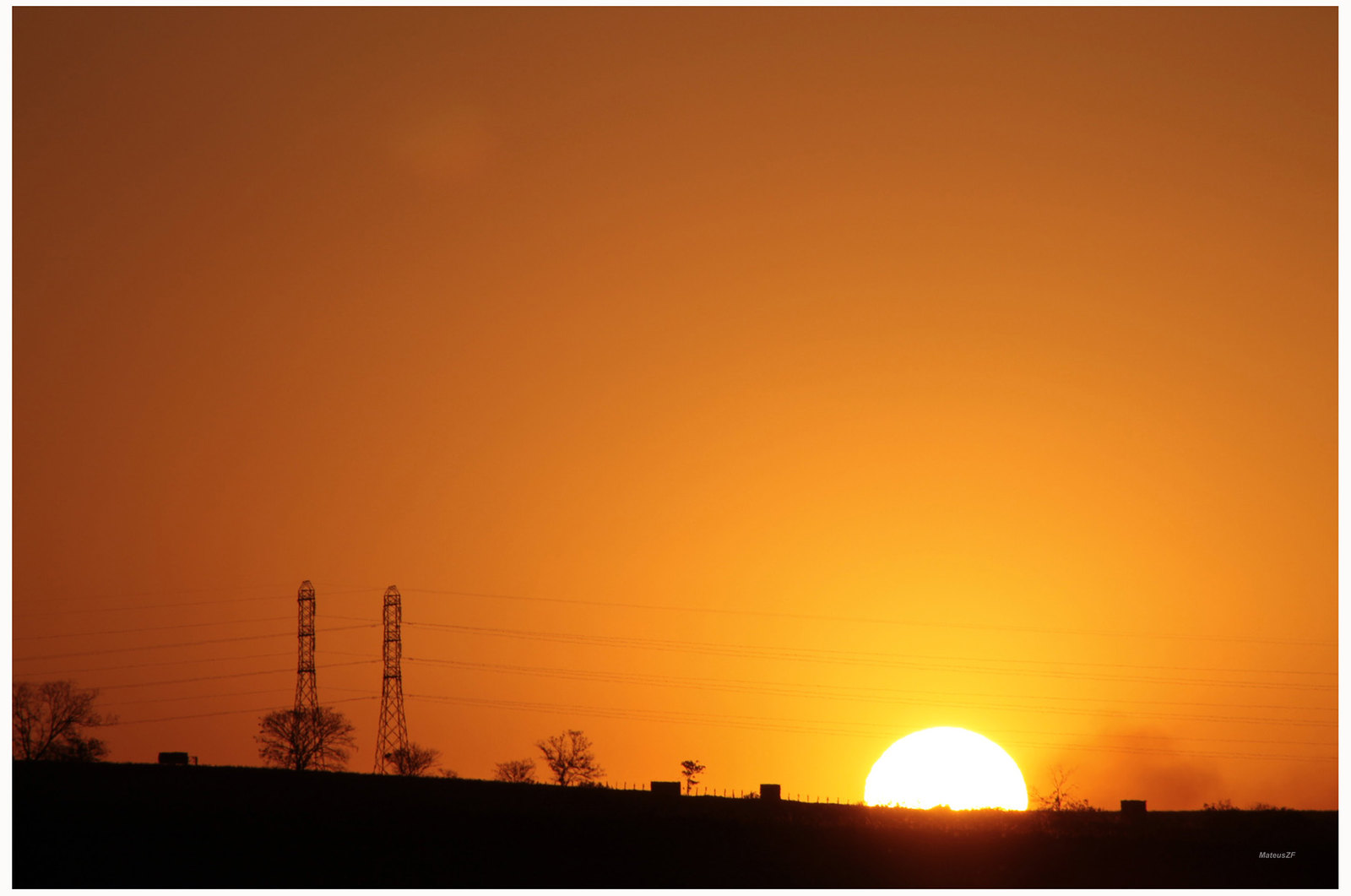 Sun setting behind electricity pylons